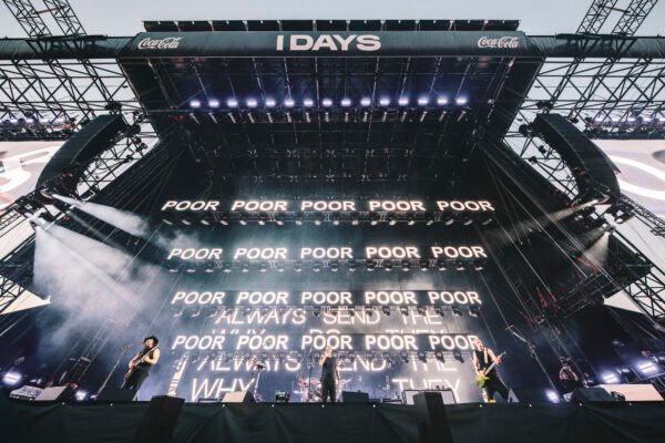 Inquadratura sul palco del concerto dei System of a Down, sugli schermi si ripete una parola. Poor, poor, poor